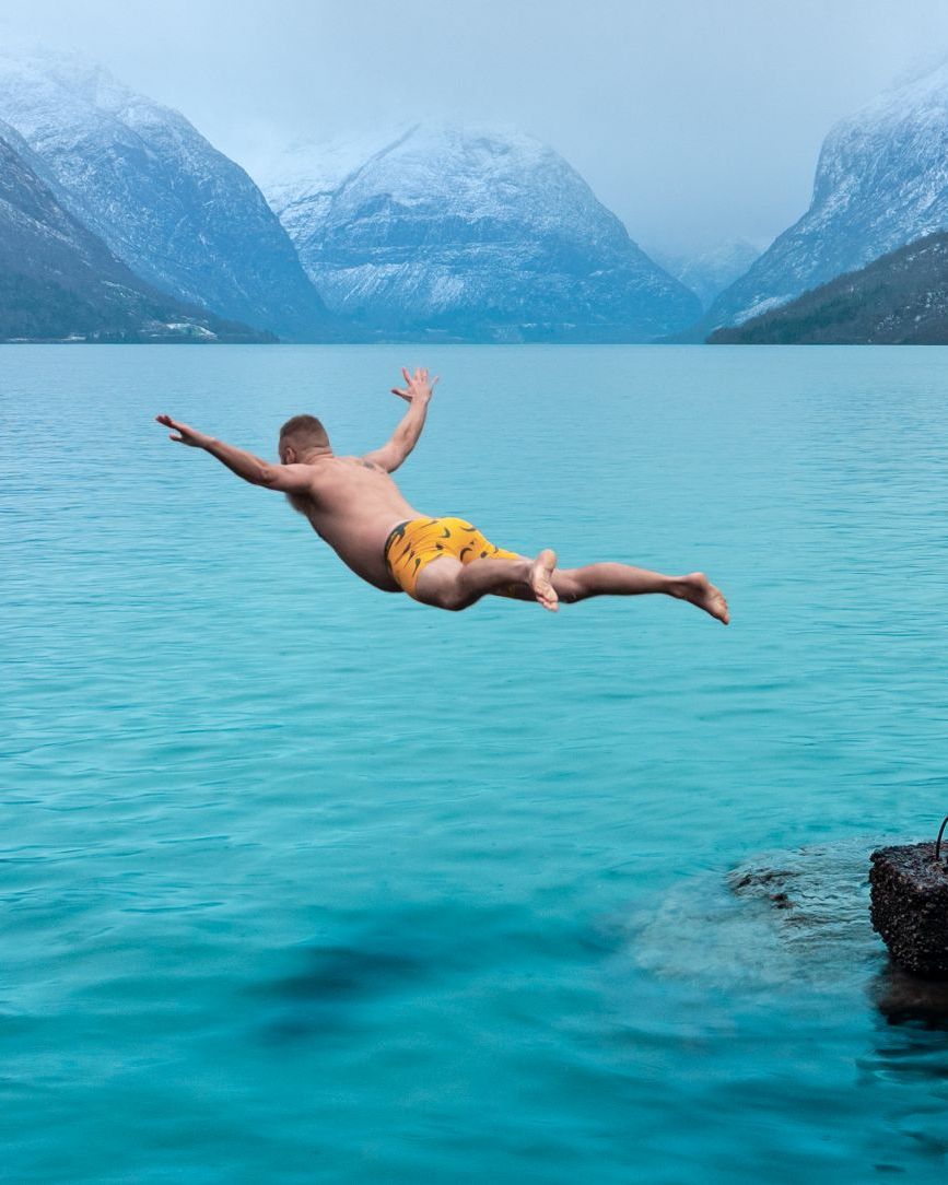 Man diving into a turquoise Norwegian fjord