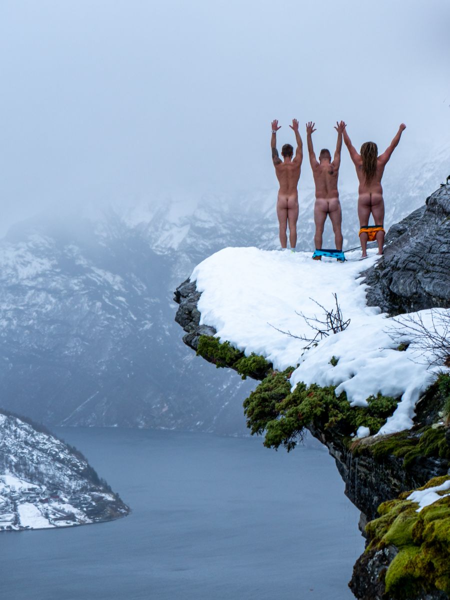 Three men in Comfyballs on a snowy cliff above a Norwegian fjord