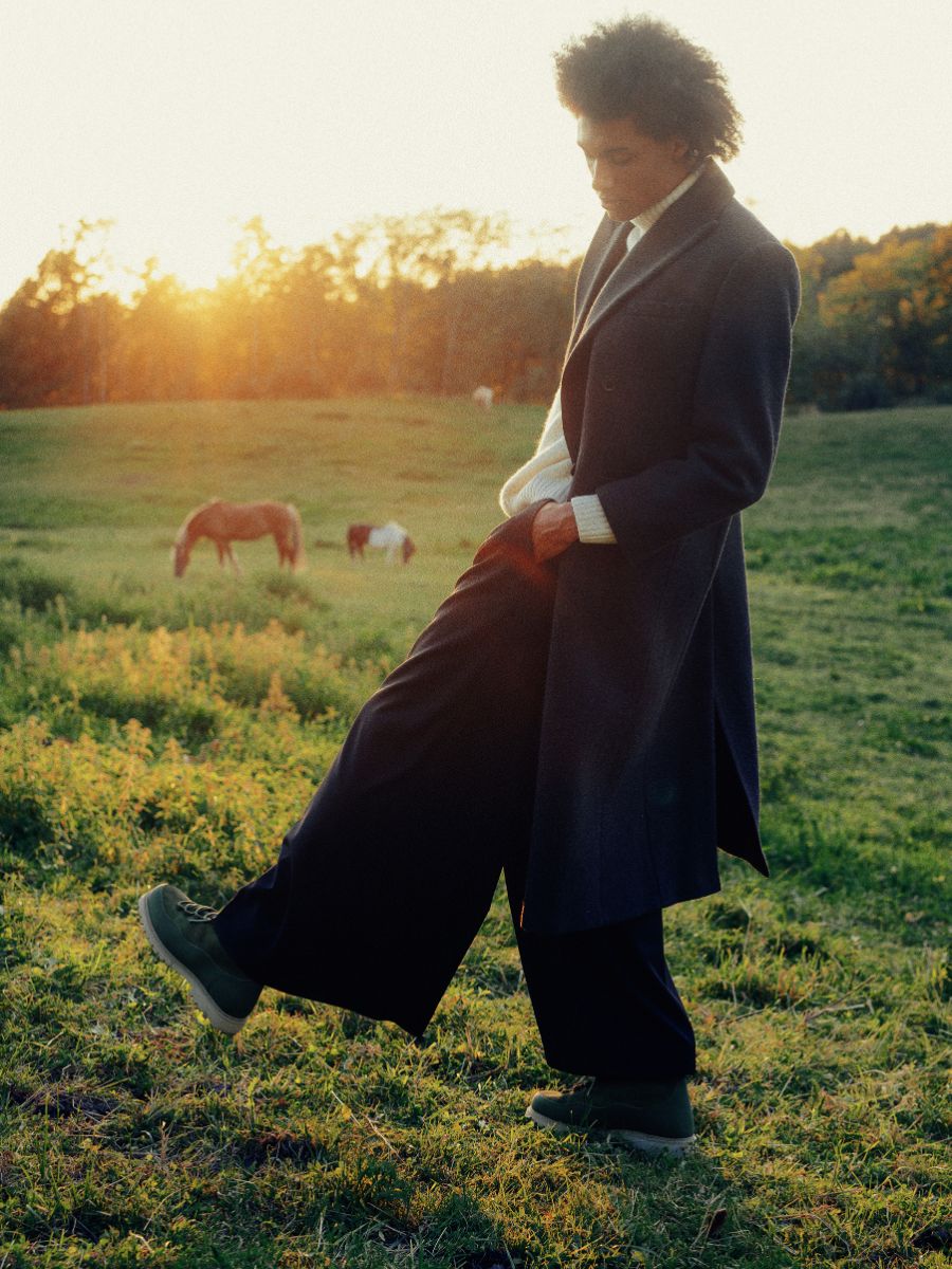 Man in New Movements boots in a field at sunset