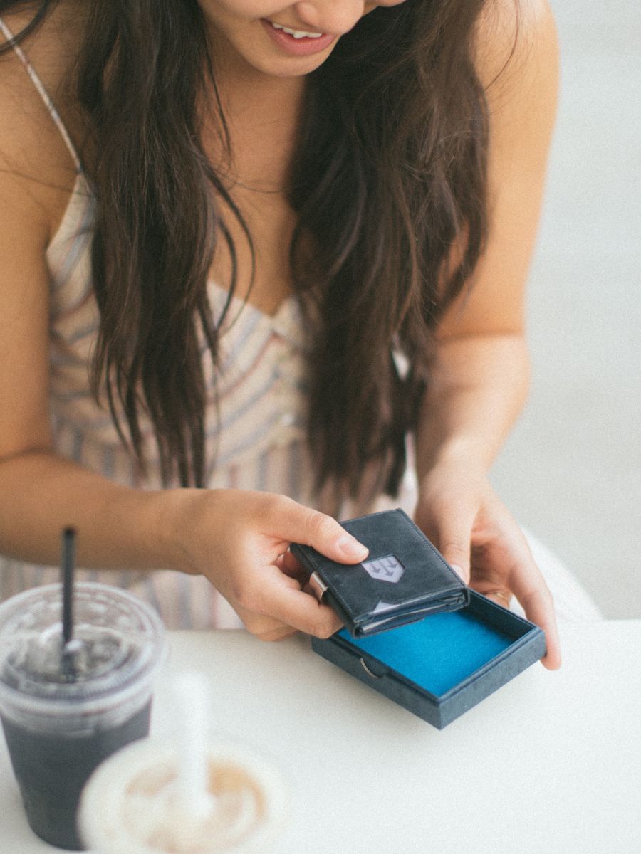 Woman opening an EXENTRI wallet at a café