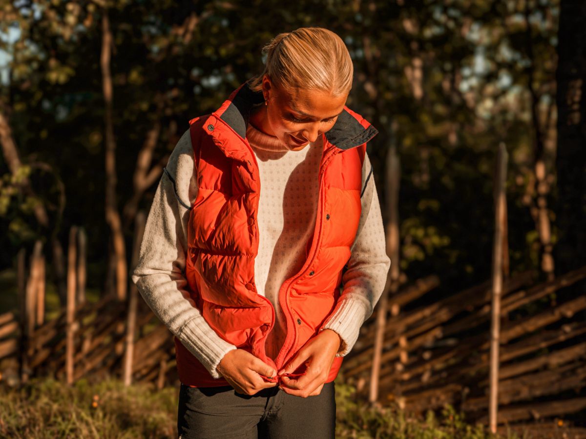 Woman in a red House of Hygge down vest in an autumn forest